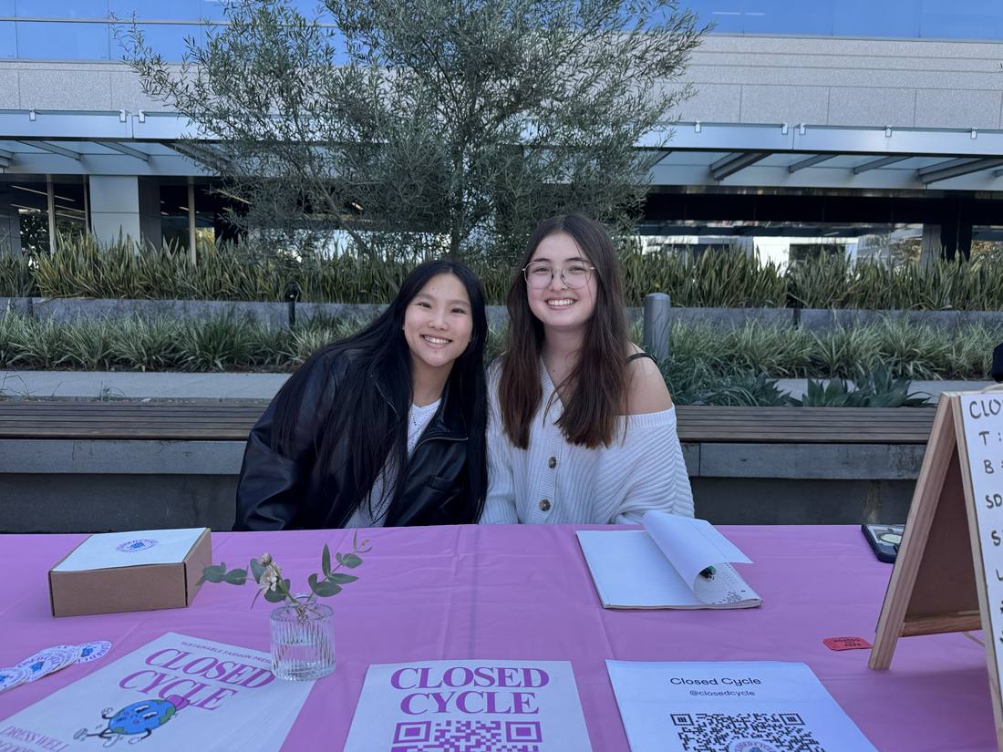 Two young entrepreneurs seated behind their product display at the 2024 fair