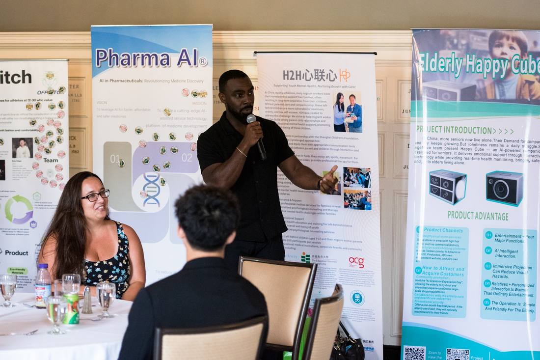 A speaker addressing participants with project posters in the background