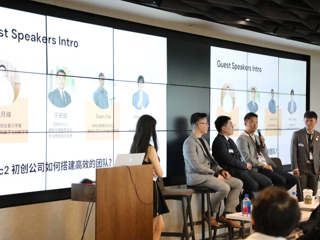 Guest speakers seated in front of a presentation screen
