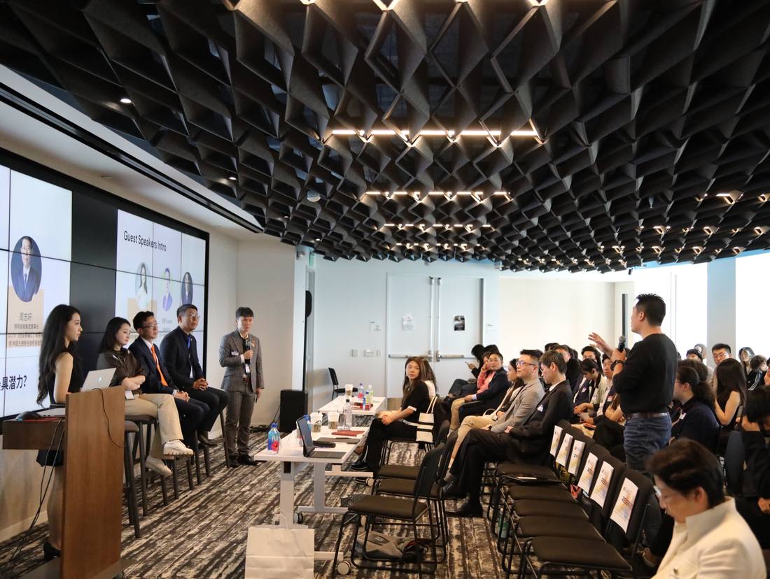 An attendee addressing a seated panel and audience during the 2025 competition