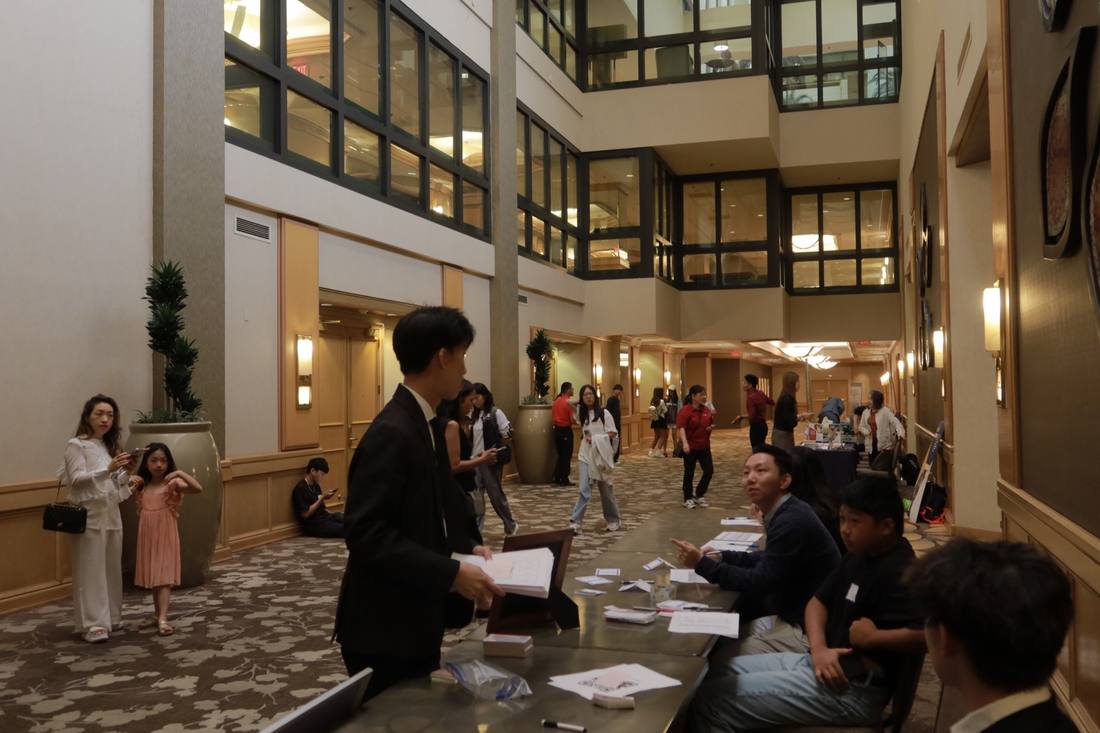 People exchanging information across a table inside the 2024 competition venue