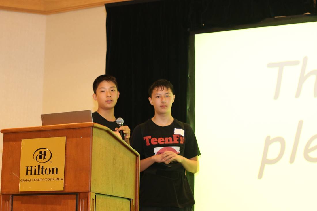 Two presenters standing beside a podium at the 2024 competition